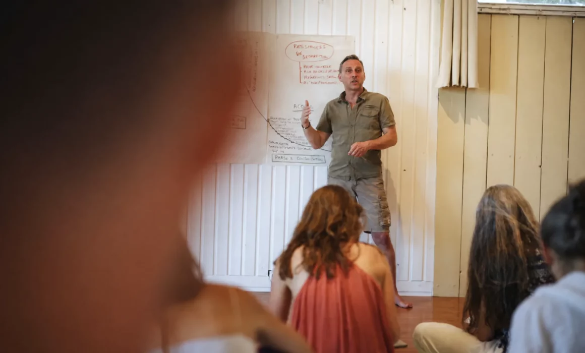 Un intervenant debout s’adresse à plusieurs participants assis dans une salle de formation intérieure.