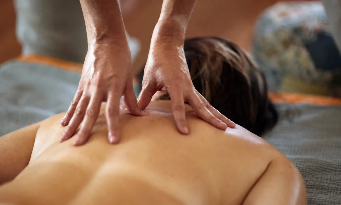 Gros plan sur un massage du haut du dos, avec les mains du praticien posées sur les épaules.