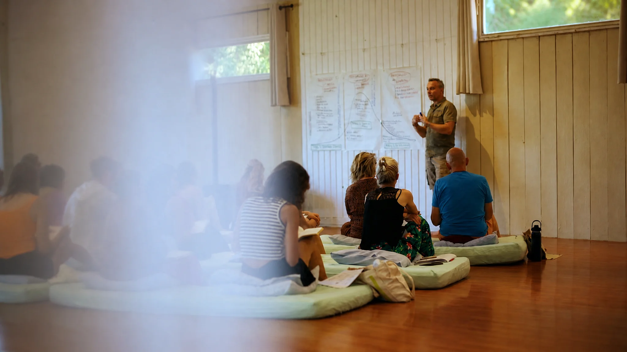 Groupe d’adultes assis sur des coussins pendant une discussion en salle